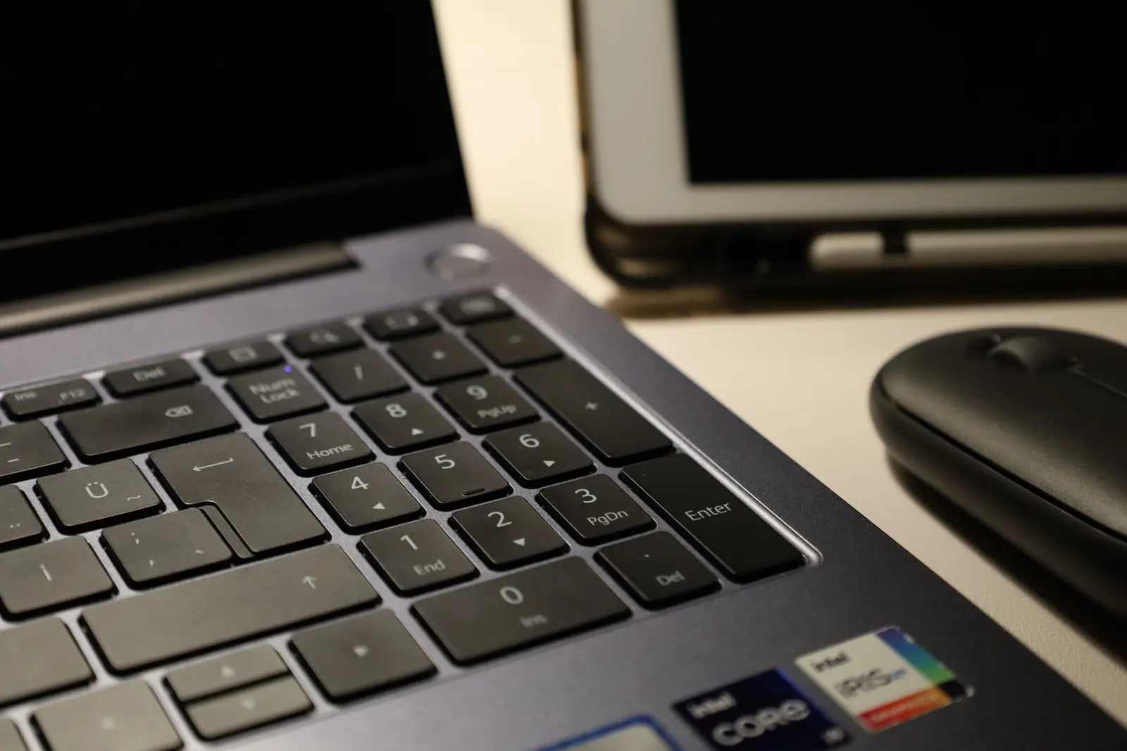 A wireless mouse beside a laptop keyboard