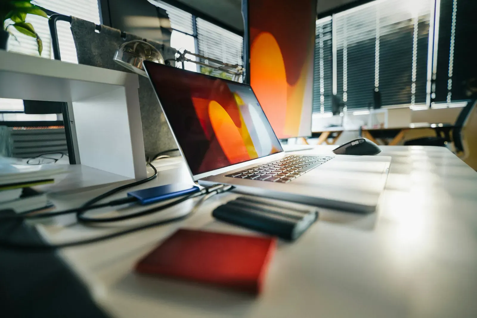 Laptop, external drives, and a monitor arranged on a modern office desk
