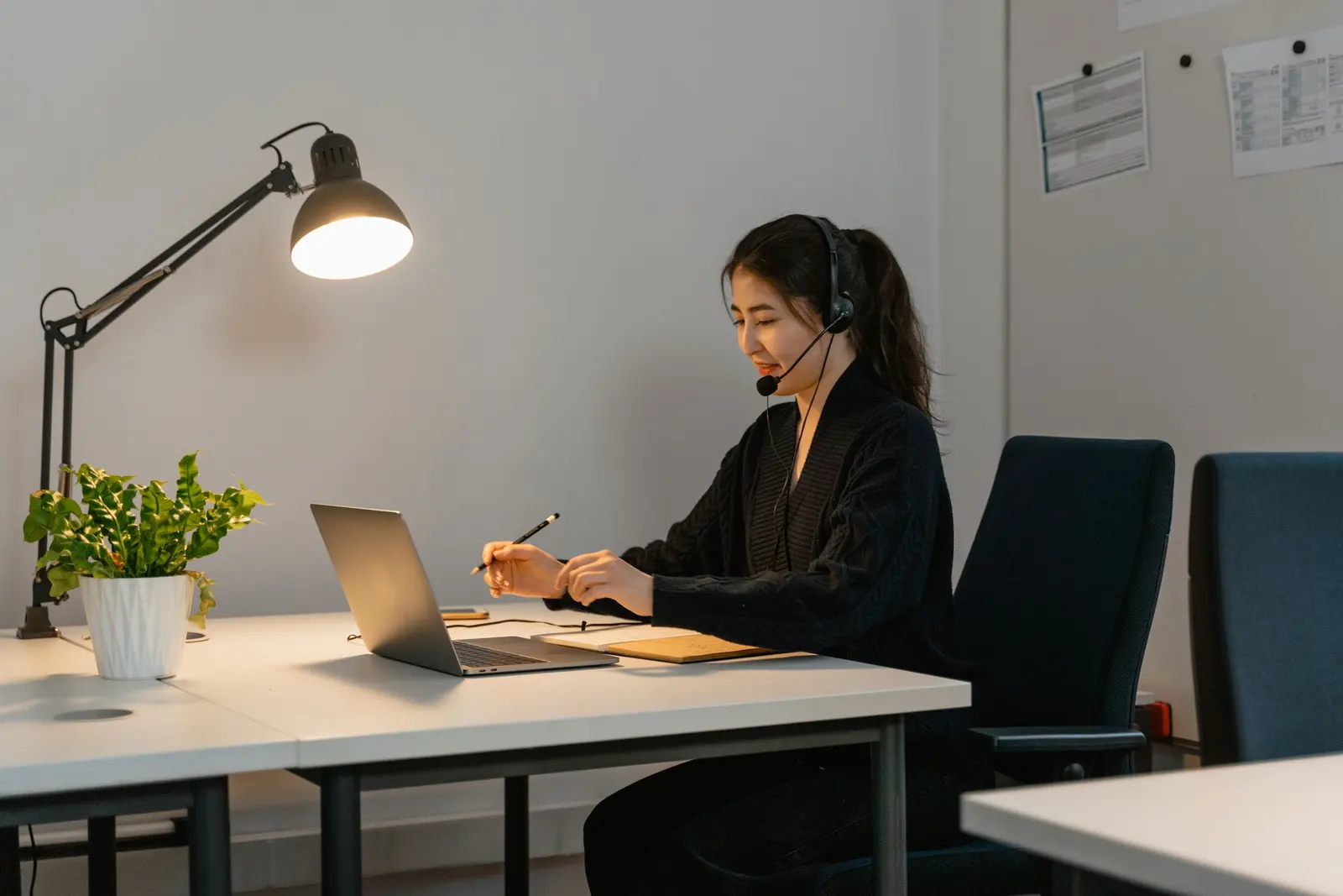 A customer support specialist wearing a headset while using a laptop