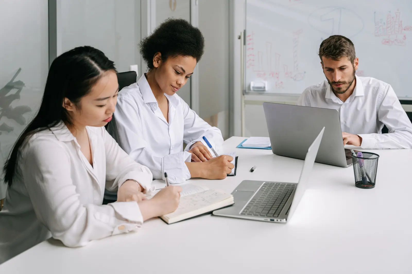 Three coworkers reviewing notes and a laptop during a training session