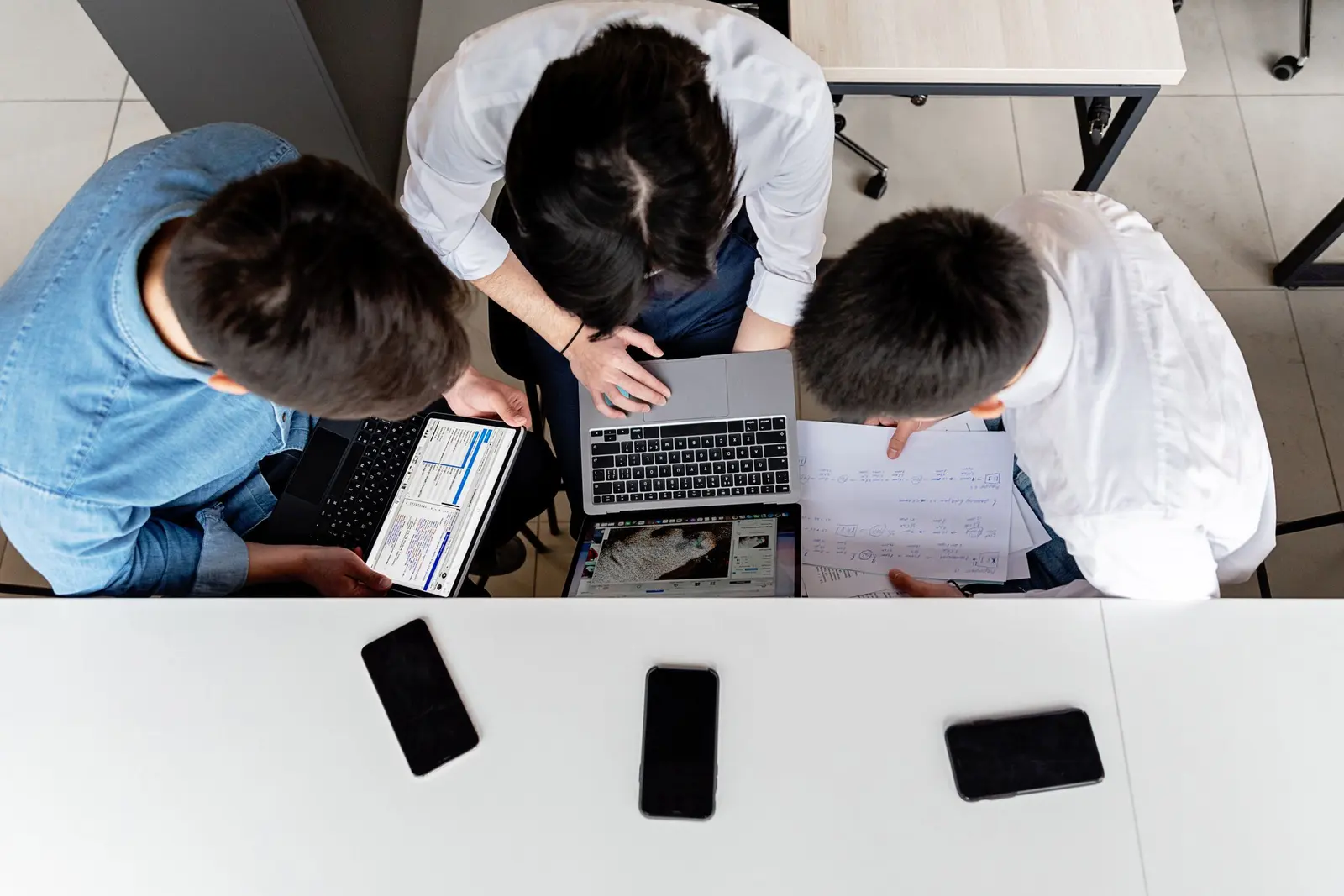 Three colleagues reviewing information together around a laptop