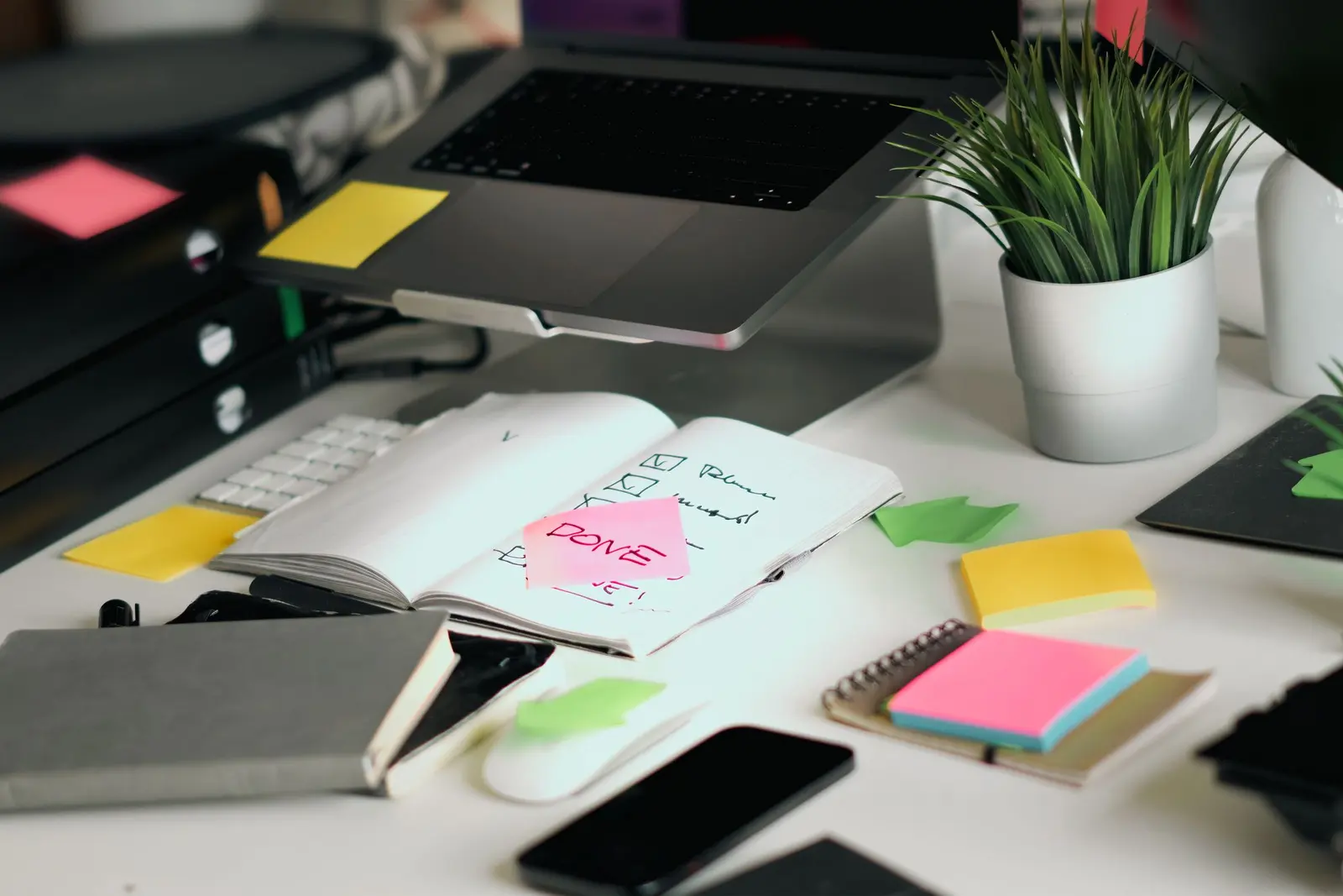 A laptop beside a notebook, workflow sketch, and sticky notes