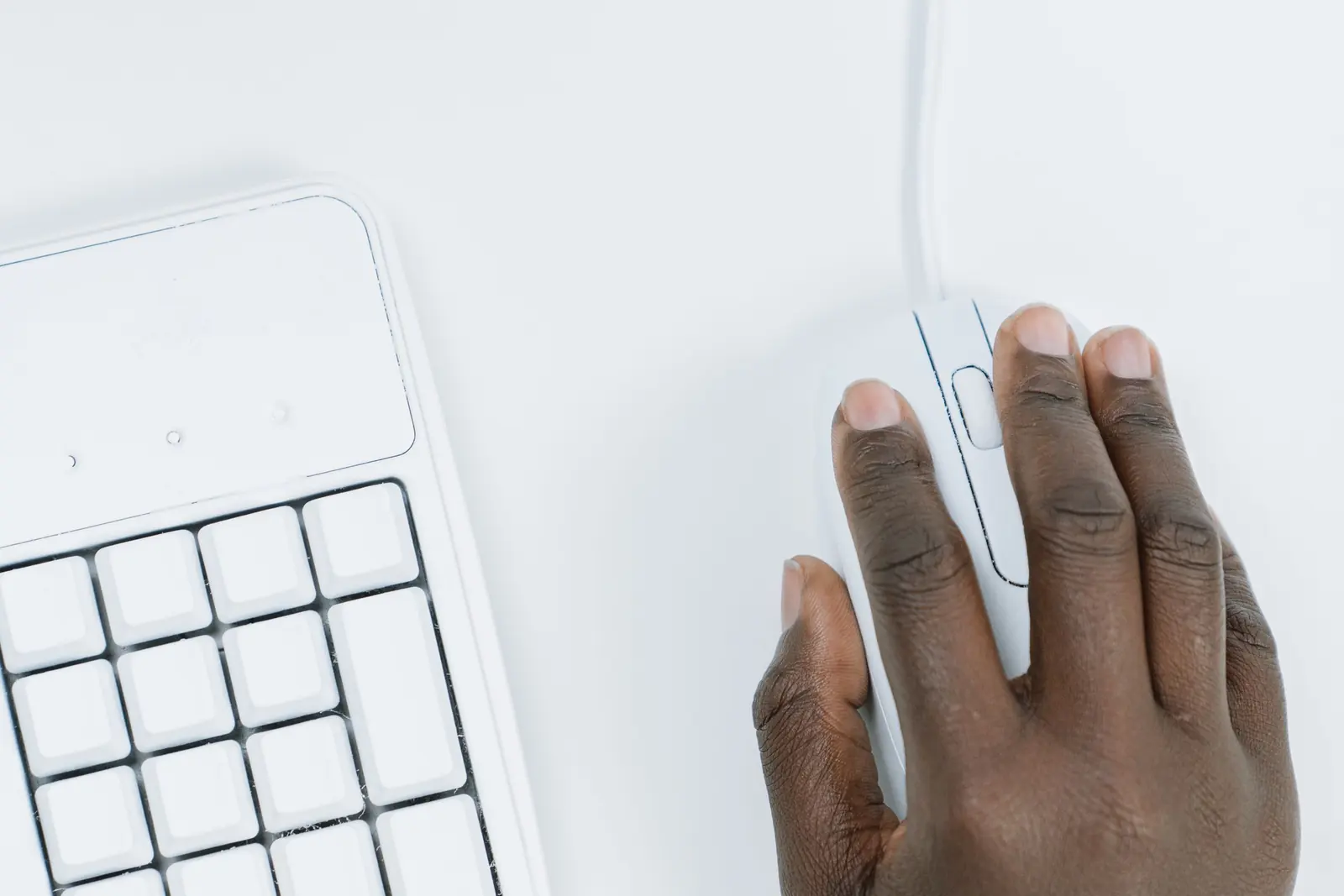 A hand using a computer mouse beside a keyboard