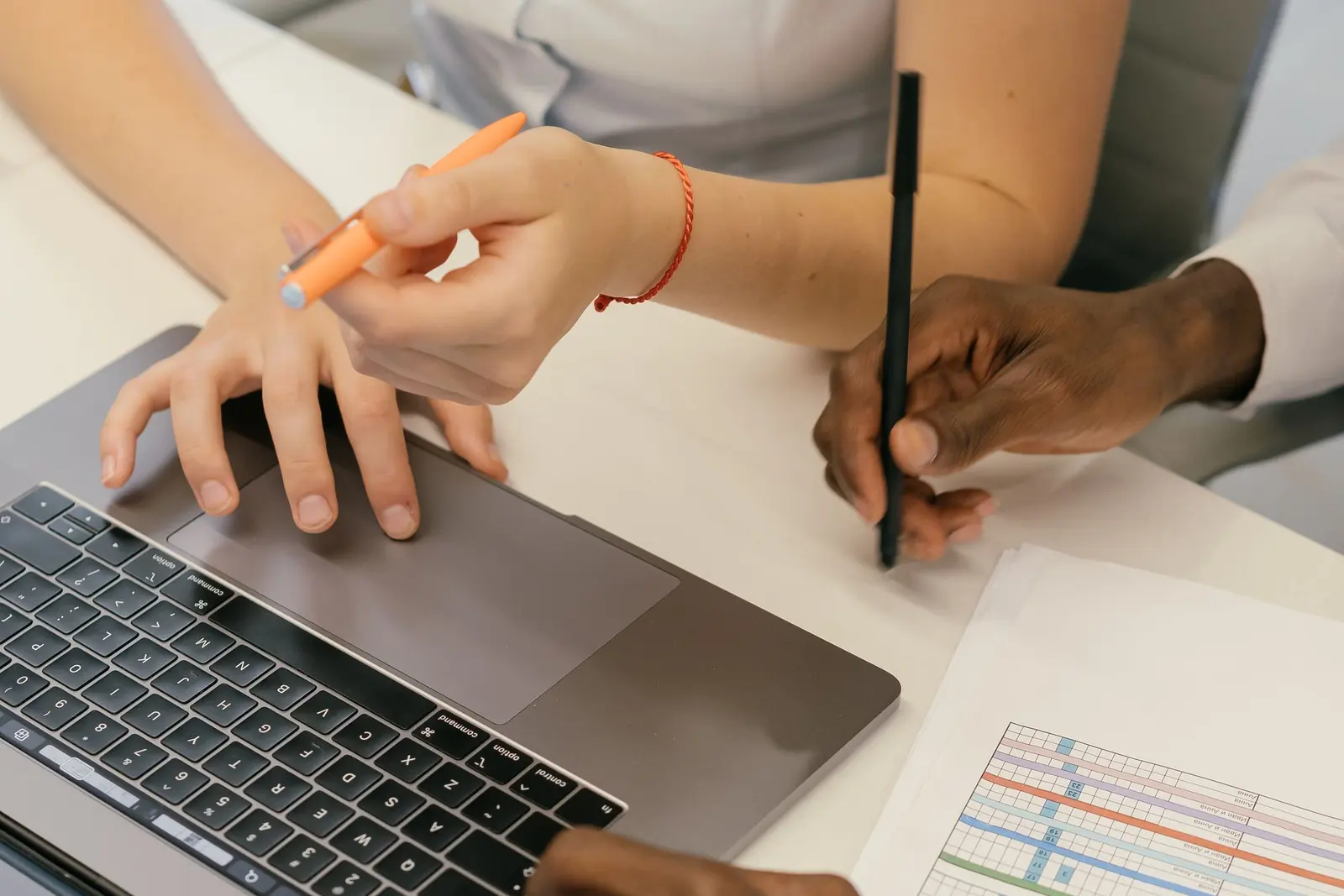 Two people comparing notes beside a laptop during a software review