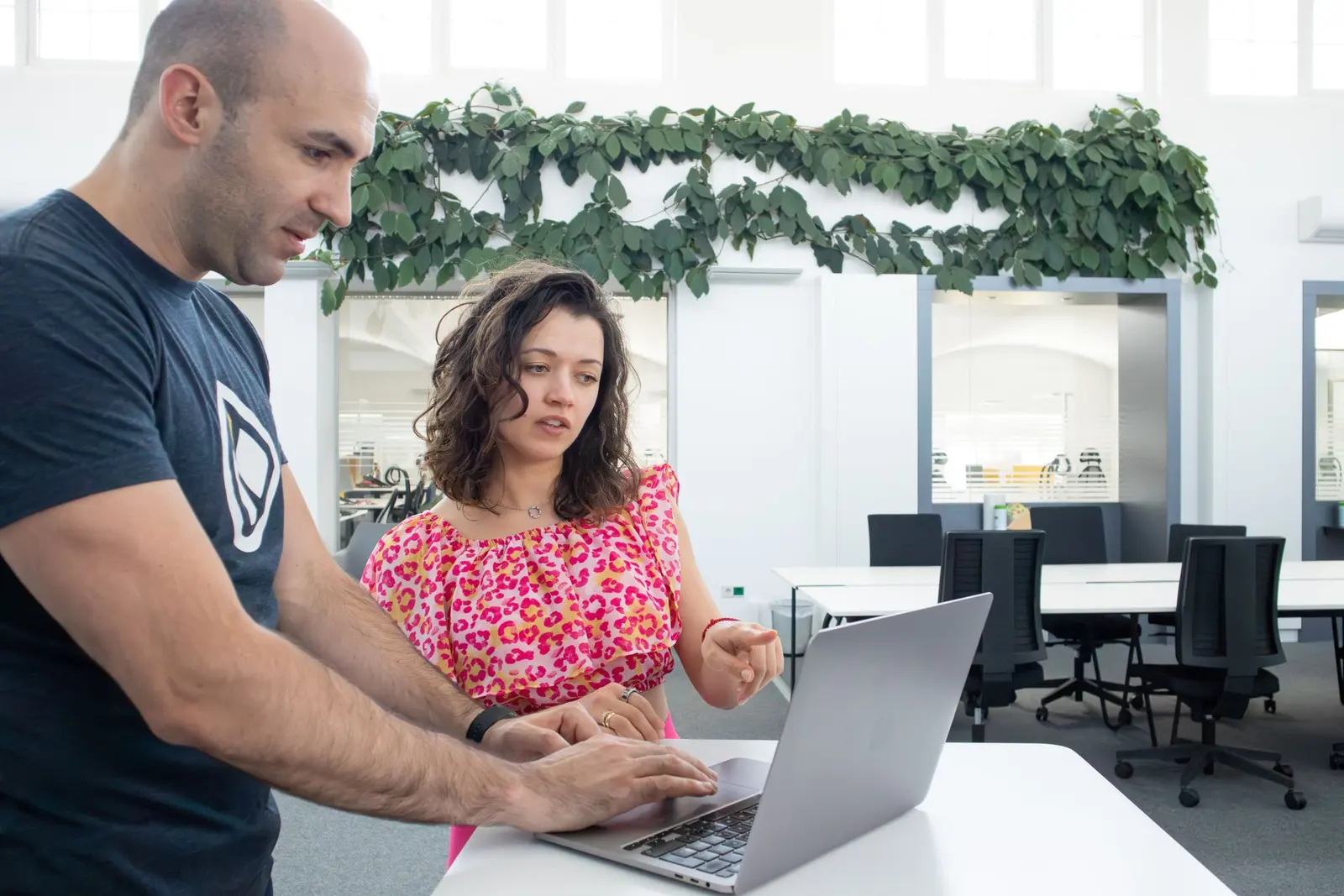Two colleagues reviewing a shared workflow on a laptop